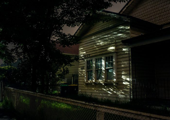 A shadowed weatherboard house photographed at night.