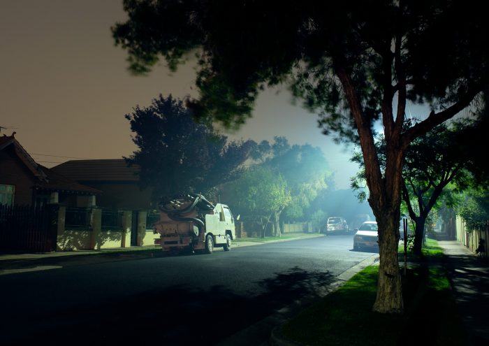 A misty street with a truck lit by a street light.